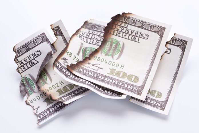 Foreclosure risks and losses 100 dollar bills torn up and burnt at the edges