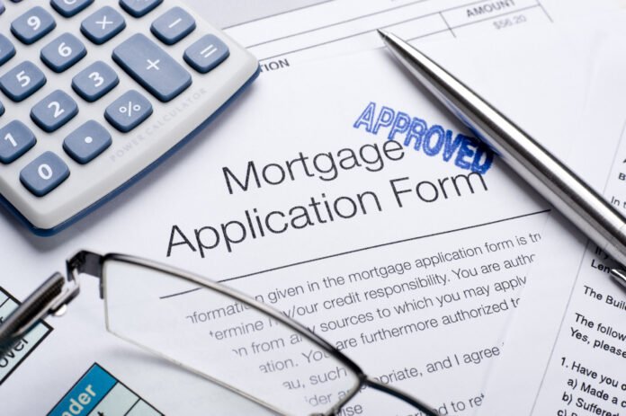 Mortgage basics Mortgage application with an approved stamp. A pair of glasses and a calculator resting on top