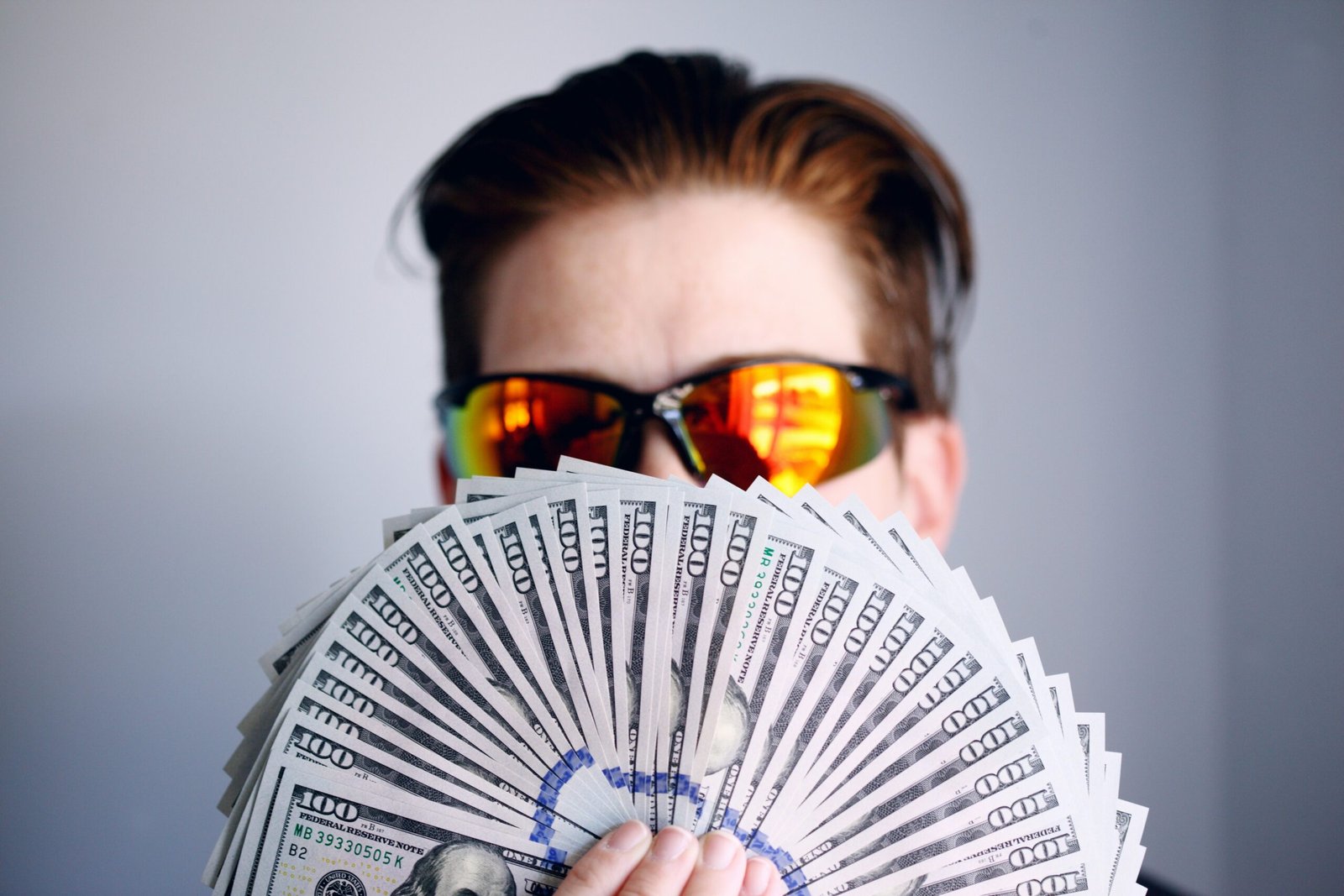 man in black framed man in black framed sunglasses holding fan of white and gray striped cards