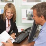 How To Pre-qualify a Hard Money Mortgage Two business people sitting around a desk with a computer looking at a brochure