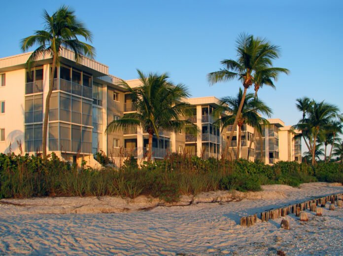 multi-family-mortgage-calculator-real-estate Multi-family residence by the beach with sand and palm trees.